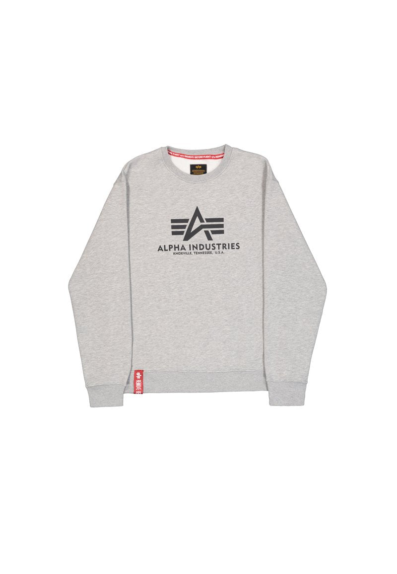 Grauer Sweatshirt mit Rundhalsausschnitt, ausgestattet mit einem schwarzen Logo "ALPHA INDUSTRIES" und einem roten Akzent-Tag am Saum. Baumwollmischung, lässiges Design.