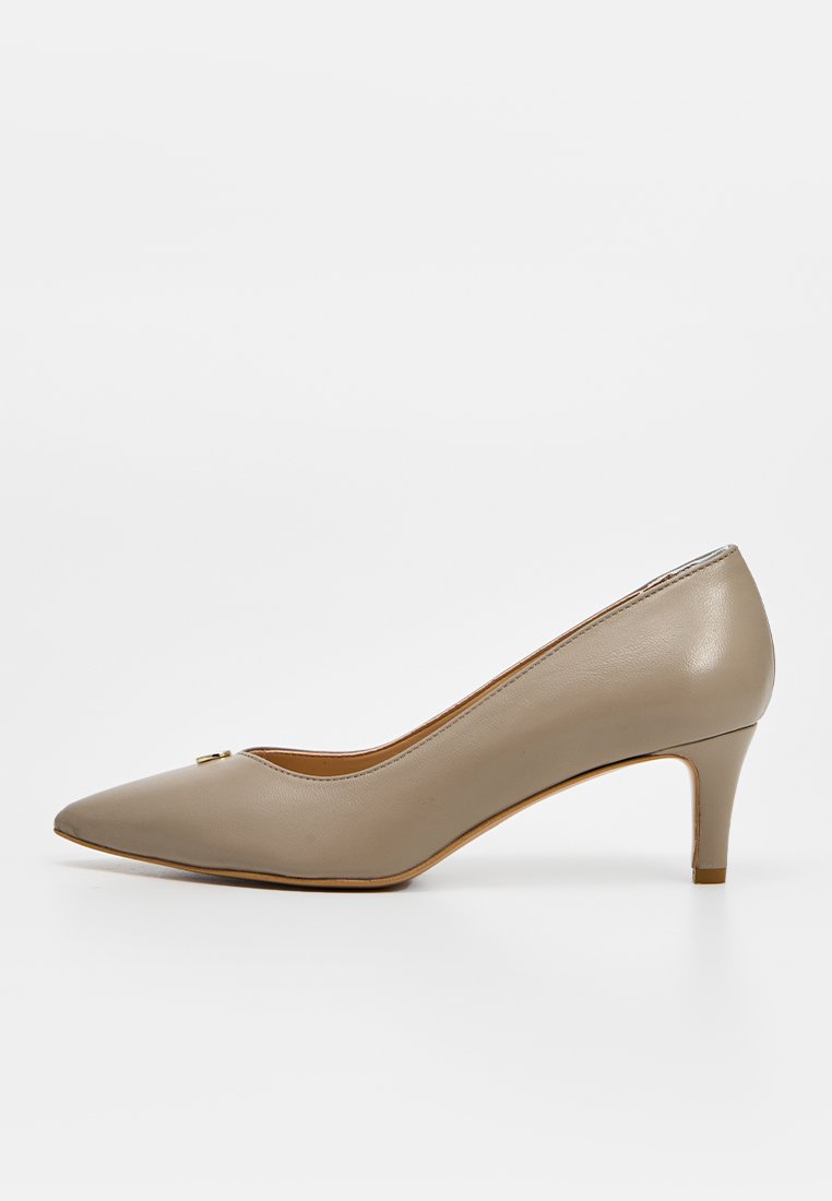 Beiger Leder-Pumps mit spitzer Spitze, niedrigem Kittenabsatz und dezentem goldfarbenem Akzent nahe der Spitze, auf weißem Hintergrund dargestellt.