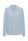 Hellblaue Bluse mit einem strukturierten Polka-Dot-Muster, V-Ausschnitt und Spitzenbesatz am Kragen und an den Manschetten. Lange Ärmel, lockere Passform.