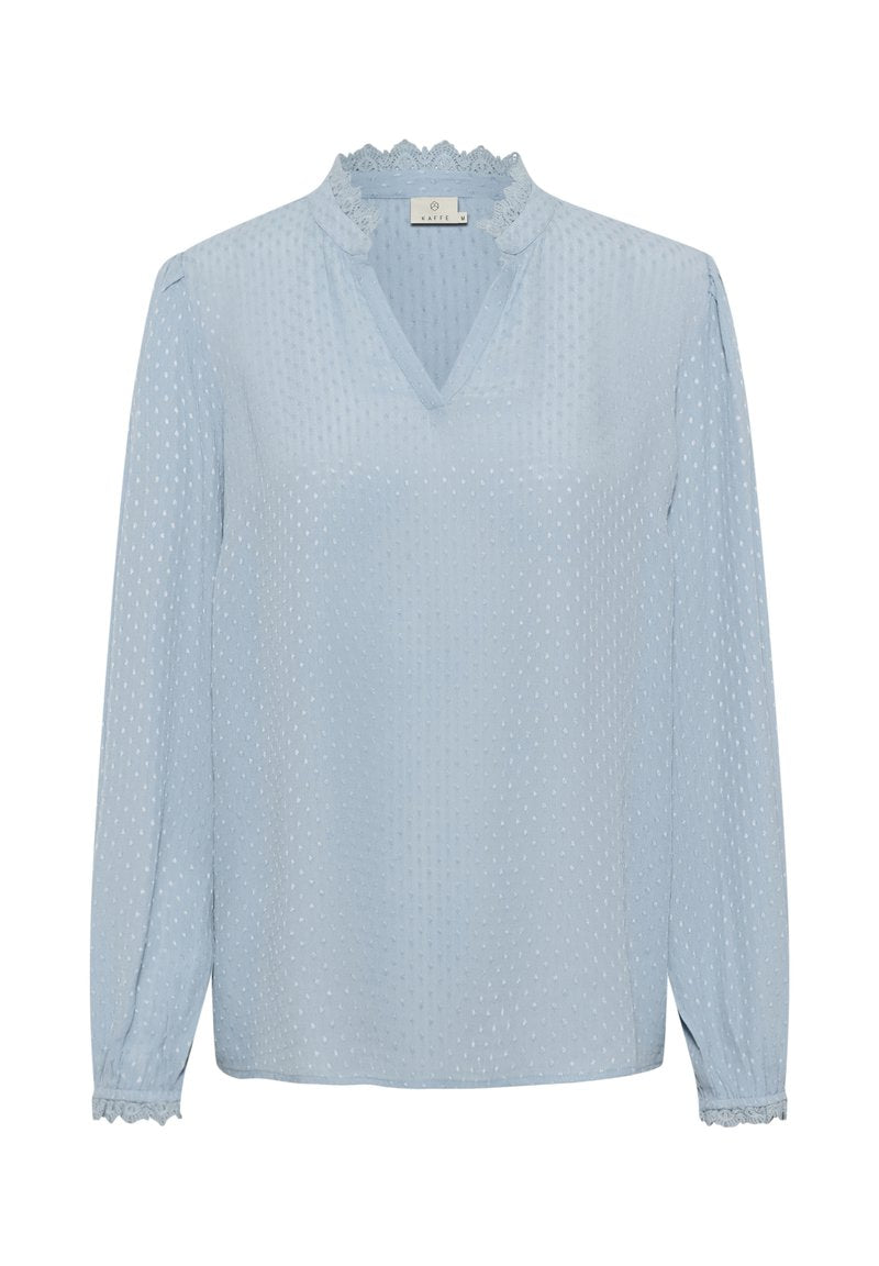 Hellblaue Bluse mit einem strukturierten Polka-Dot-Muster, V-Ausschnitt und Spitzenbesatz am Kragen und an den Manschetten. Lange Ärmel, lockere Passform.
