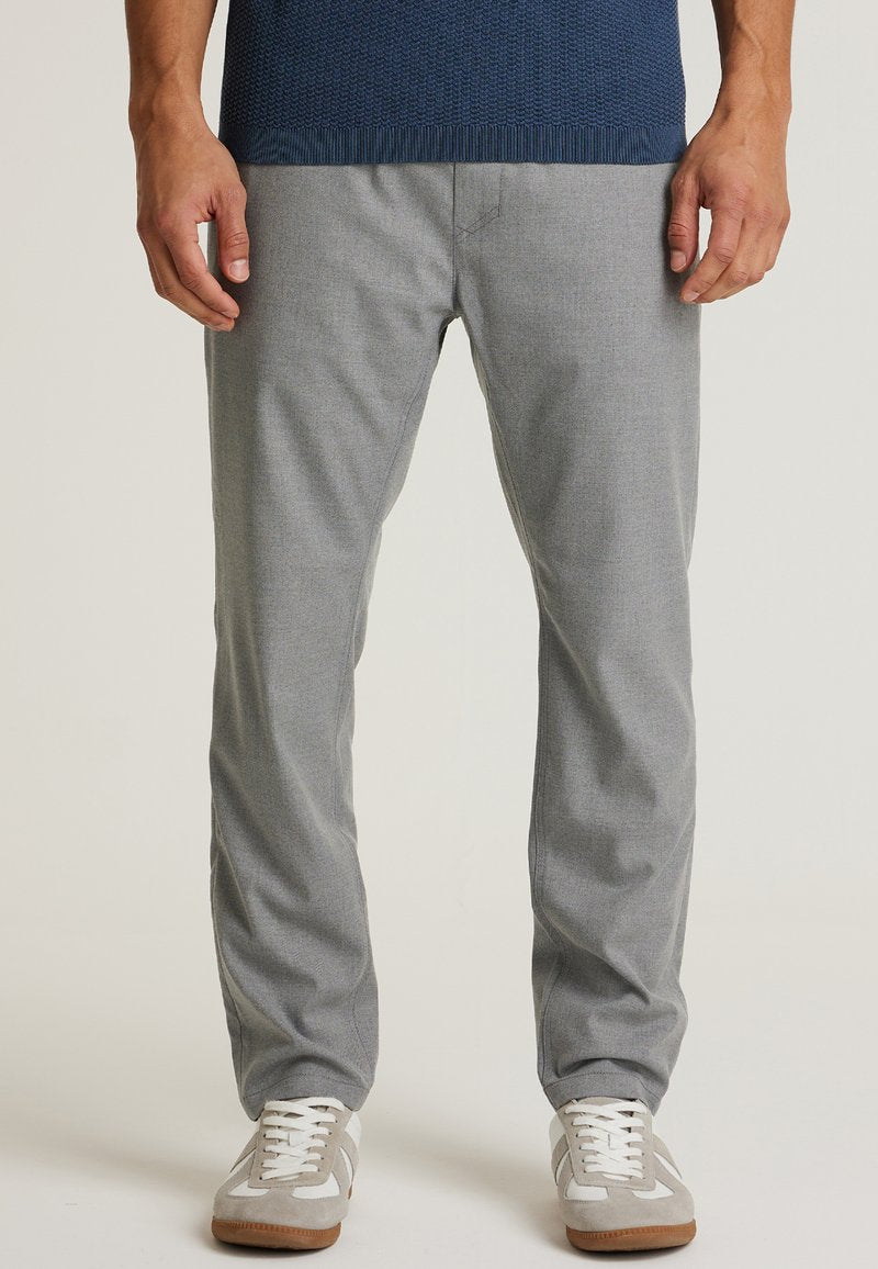 Graue Chino-Hosen mit glatter Textur, schmalem Schnitt und subtilen Stickdetails, kombiniert mit hellgrauen und weißen Sneakers.