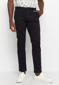 Schwarze Baumwollhose im Slim-Fit-Stil mit Knopfverschluss, seitlichen Taschen und glatter Textur, kombiniert mit weißen Sneakers.