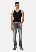 Schwarzes ärmelloses Tanktop, ausgebleichte graue Jeans mit Used-Details und graue Sneakers mit schwarz-weißen Akzenten. Lässige Outfit-Präsentation.