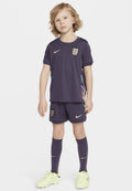 Nike Kinder-Fußballset in Dunkelviolett mit goldenen Akzenten. Enthält ein Trikot, Shorts, Kniestrümpfe und leuchtend gelbe Fußballschuhe.