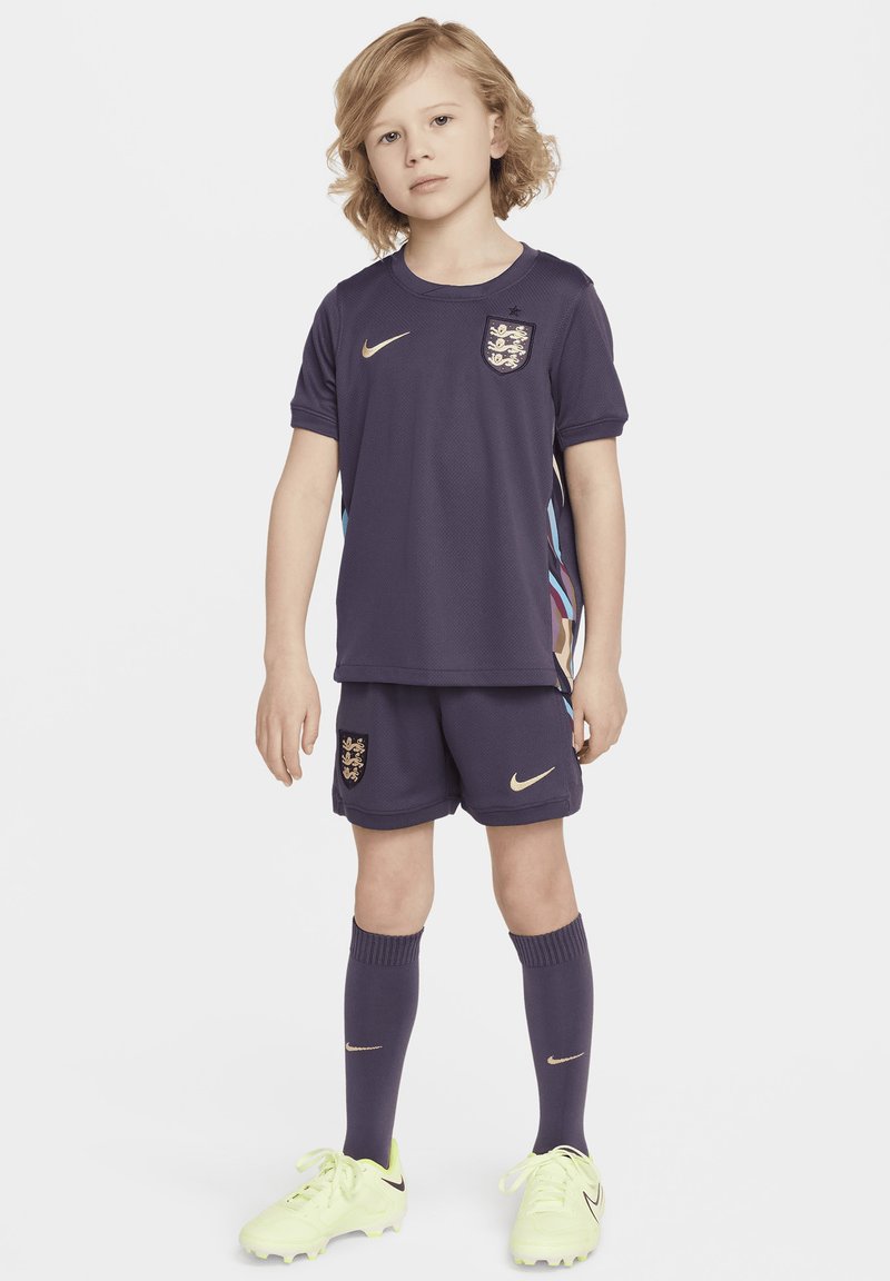 Nike Kinder-Fußballset in Dunkelviolett mit goldenen Akzenten. Enthält ein Trikot, Shorts, Kniestrümpfe und leuchtend gelbe Fußballschuhe.
