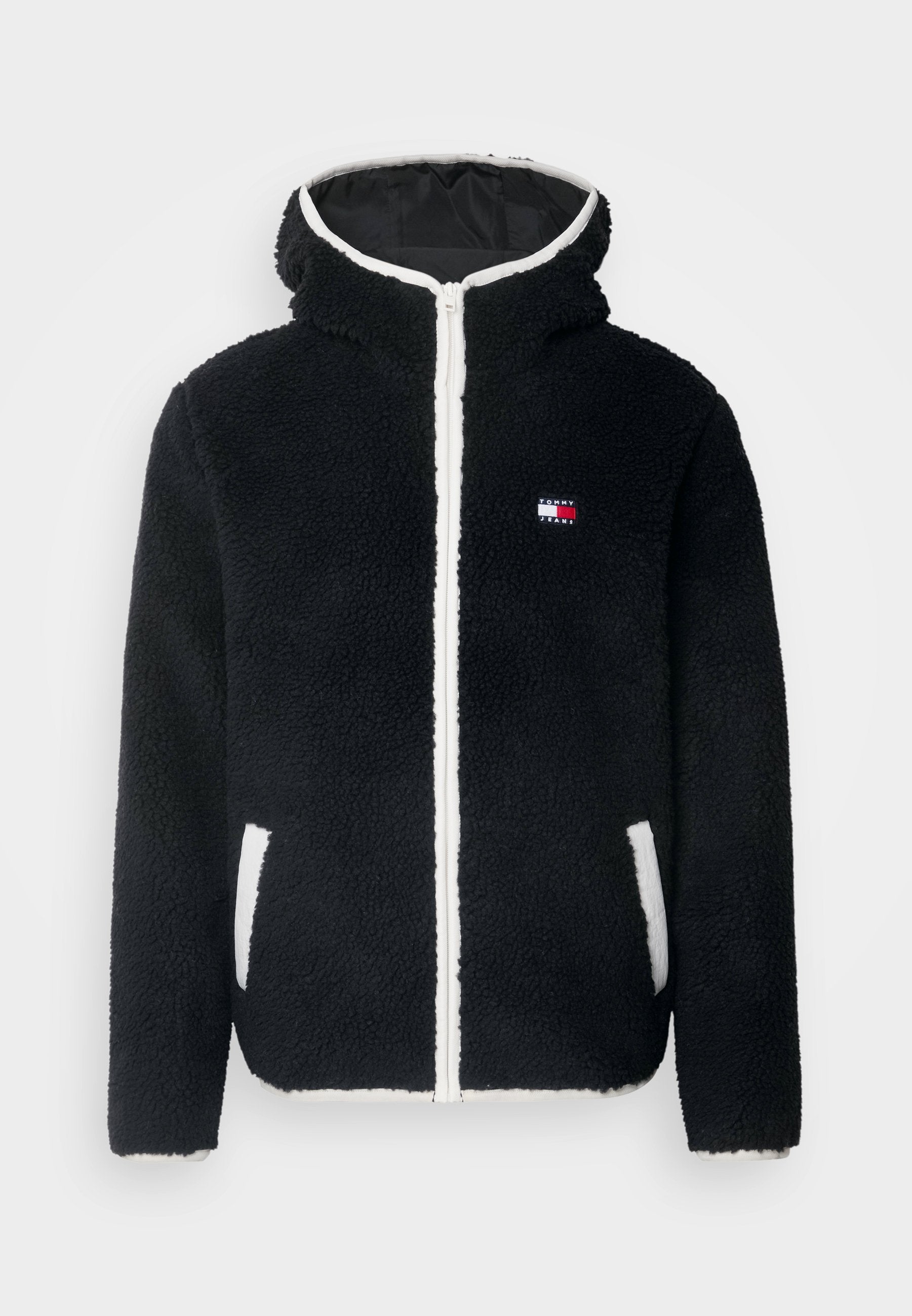 Schwarze Fleecejacke mit Kapuze, ausgestattet mit einem weißen Reißverschluss und Taschen; kleines Logo in Rot, Weiß und Blau auf der linken Brust. Weicher Stoff.